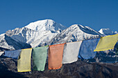 View from the roof of the buddhist Gompa with prayer flags of Dzong, Jhong, village at the Annapurna Circuit Trek. In the background Tilicho Peak (7134 m) and Khangsar Kang (7485 m), Mustang, Nepal, Himalaya, Asia