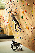 Paraplegic woman rock climbing in gym