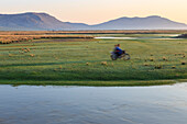 Nomads on motorcycle pass in a blur, river and distant gers, dawn, Nomad camp, Gurvanbulag, Bulgan, Northern Mongolia, Central Asia, Asia
