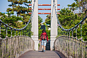 Woman walking over a suspension bridge over river Yongyeon in Jeju Si on Jeju Island