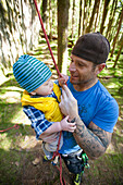 A man holds his son before rock climbing.