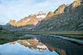 Runners reflection on the lake Combal at sun rise during the UTMB Ultra Trail du Mont-Blanc