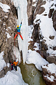 A man and woman ice climbing a frozen waterfall in the Ouray Ice Park, Ouray, Colorado.
