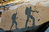 The shadows of two backpackers on a large rock en route Conway Peak, British Columbia, Canada.