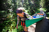 A young woman portages her canoe during a canoe trip through Bowron Lake Provincial Park.