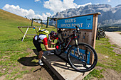 Mountain biker repairing his bike at the service point of the Emilio Comici hut at Langkofel, Trentino South Tyrol, Italy