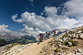 Mountain bikers at Langkofel, behind it from right to left Sella group, Puez group, Geisler group, Trentino South Tyrol, Italy