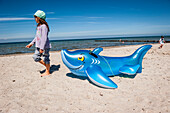 girl pulling a rubber shark, rubber toy on the beach, seaside, Poel Island, Wismar, Baltic Sea, Germany, Europe, summer