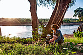 A young woman observes the early morning light while camping in Samburu National Park, Kenya, East Africa, Africa