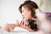 Mother kissing feet of baby girl