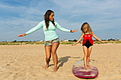 Mutter bringt Tochter am Strand das Surfen bei