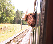 Hispanic woman with head out train window