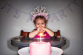 Caucasian baby girl admiring birthday cupcake