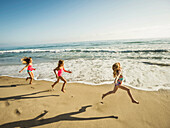 Caucasian sisters running on beach