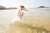 Caucasian girl splashing in waves on beach