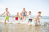 Caucasian children playing in waves on beach