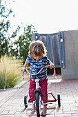 Caucasian boy riding tricycle in backyard