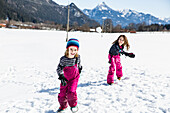 girl throwing a snowball towards a boy during a snowball fight in winter, Pfronten, Allgaeu, Bavaria, Germany