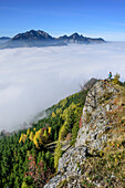 Woman hiking looking towards fog in the valley of Inn and Mangfall range with Wendelstein, Rehleitenkopf, Mangfall range, Bavarian Alps, Upper Bavaria, Bavaria, Germany