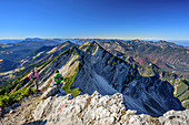 Zwei Personen beim Wandern rasten am Sonntagshorn, Reifelberge und Chiemgauer Alpen im Hintergrund, Sonntagshorn, Chiemgauer Alpen, Salzburg, Österreich