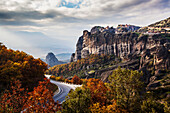 Monasteries perched on cliffs and a winding road in autumn foliage, Meteora, Greece