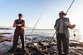 Men fishing at dusk at the water's edge of the Mediterranean, Mount Casius in the distance, Cevlik, Turkey