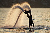 Silhouette of backlit flyboarder diving vertically with arms stretched out, Torba, Mugla Province, Turkey