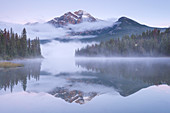 A misty Pyramid Mountain reflected in Pyramid Lake at dawn, Jasper National Park, Canadian Rockies, UNESCO World Heritage Site, Alberta, Canada, North America