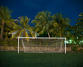 Soccer goal on field against palm trees at dusk
