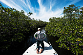Fisherman on a flats boat looking for baby tarpon, snook or anything else swimming in the mangrove channels near Key Largo Florida.