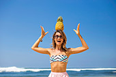 Young woman playing with pineapple