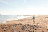 Woman walking along beach at Reid State Park