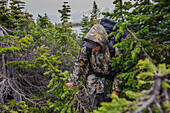 A boy struggles through small pine trees in a rain storm on the third and stormy day of Troop 693's six day backpack trip through the High Uintas Wilderness Area, Uintas Range, Utah