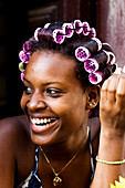 A local Cuban girl smiles with curlers in her hair in Havana, Cuba.