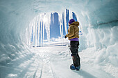 A woman looks out at the frozen Ross Sea from a hole in an iceberg.