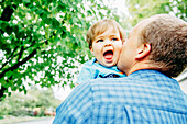 Father kissing cheek of baby son outdoors