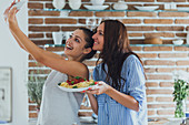 Caucasian women taking selfie in kitchen with pasta