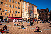 touristes et passants prenant le soleil sur la piazza del campo de sienne, sienne, italie, union europeenne