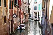 Gondolier paddling on a canal between buildings Venice, Italy