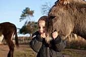 Cute girl embracing donkey on field