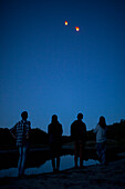 Rear view of friends looking at paper lanterns flying in clear blue sky