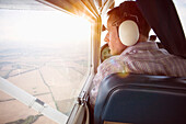 Rear view of man looking through private airplane window