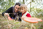 Mother and daughter exploring mushroom on field