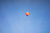 Low angle view of buoy in mid-air against blue sky