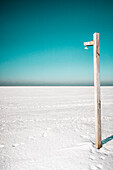 Wooden post on snowy landscape against clear sky