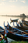 Boats on the Taungthaman Lake near Amarapura with the U Bein teak bridge behind, Mandalay, Myanmar Burma, Southeast Asia