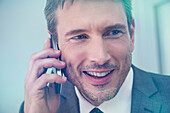 Businessman talking on cell phone, smiling cheerfully