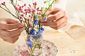 Hispanic woman arranging flowers in glass cup