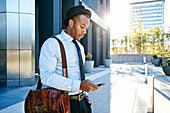 Black businessman using cell phone outside office building