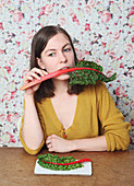 Woman eating chard while sitting at table
